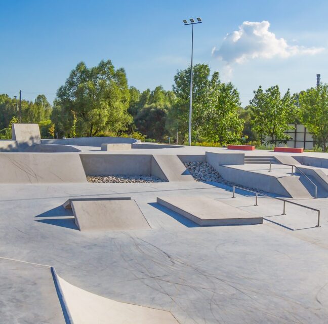 An empty concrete skate park with ramps and bowls on a sunny day
