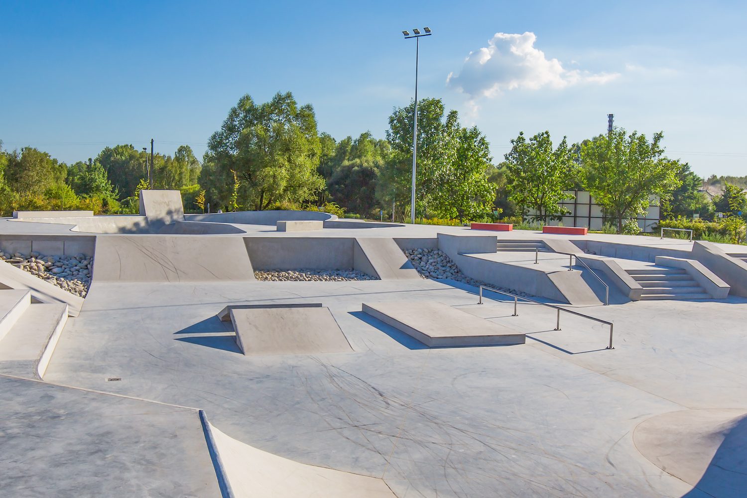 An empty concrete skate park with ramps and bowls on a sunny day