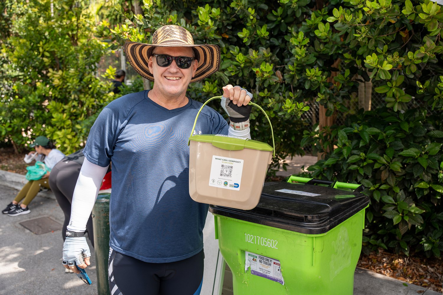 Pinecrest resident with a kitchen compost pail beside a curbside organics cart