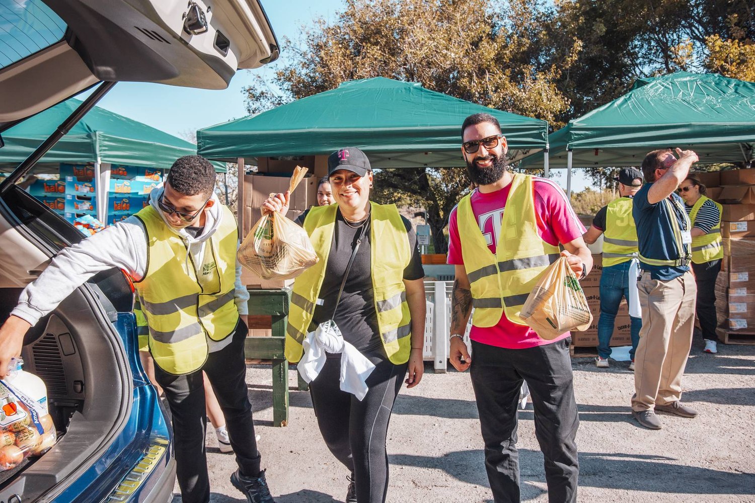 Volunteers in safety vests loading groceries into a car at a Farm Share distribution